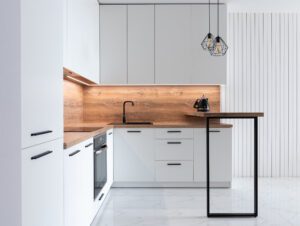 A white, modern kitchen with a wood backsplash