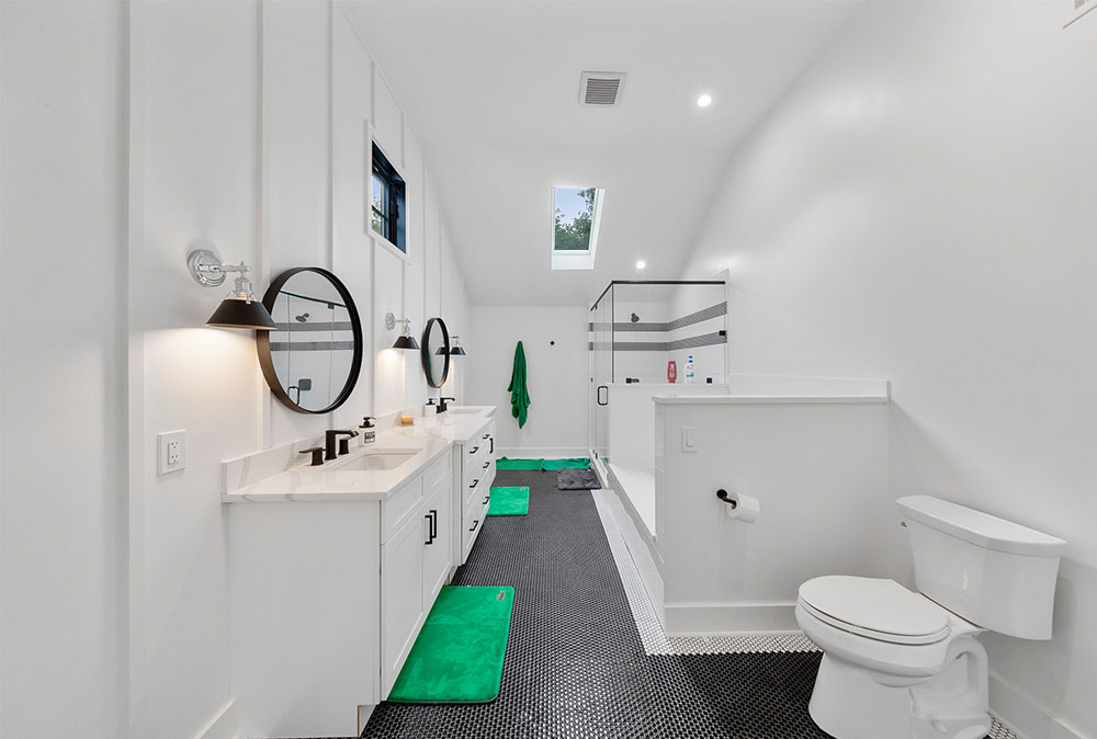 Dual sink white bathroom with green rugs