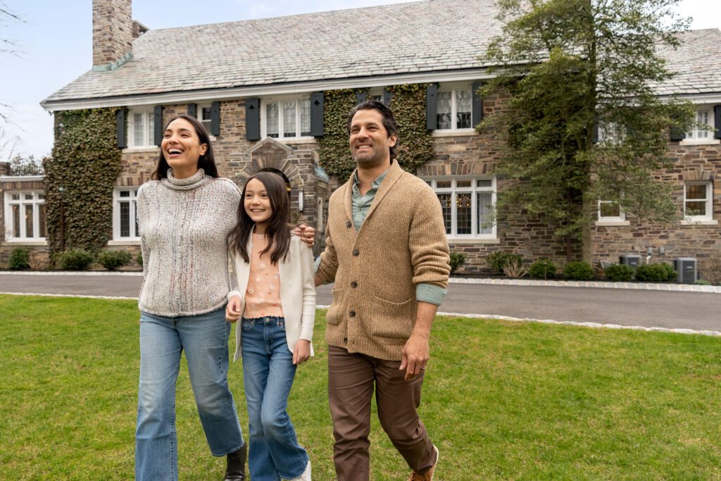 Happy, smiling family walking on grass with custom home in background