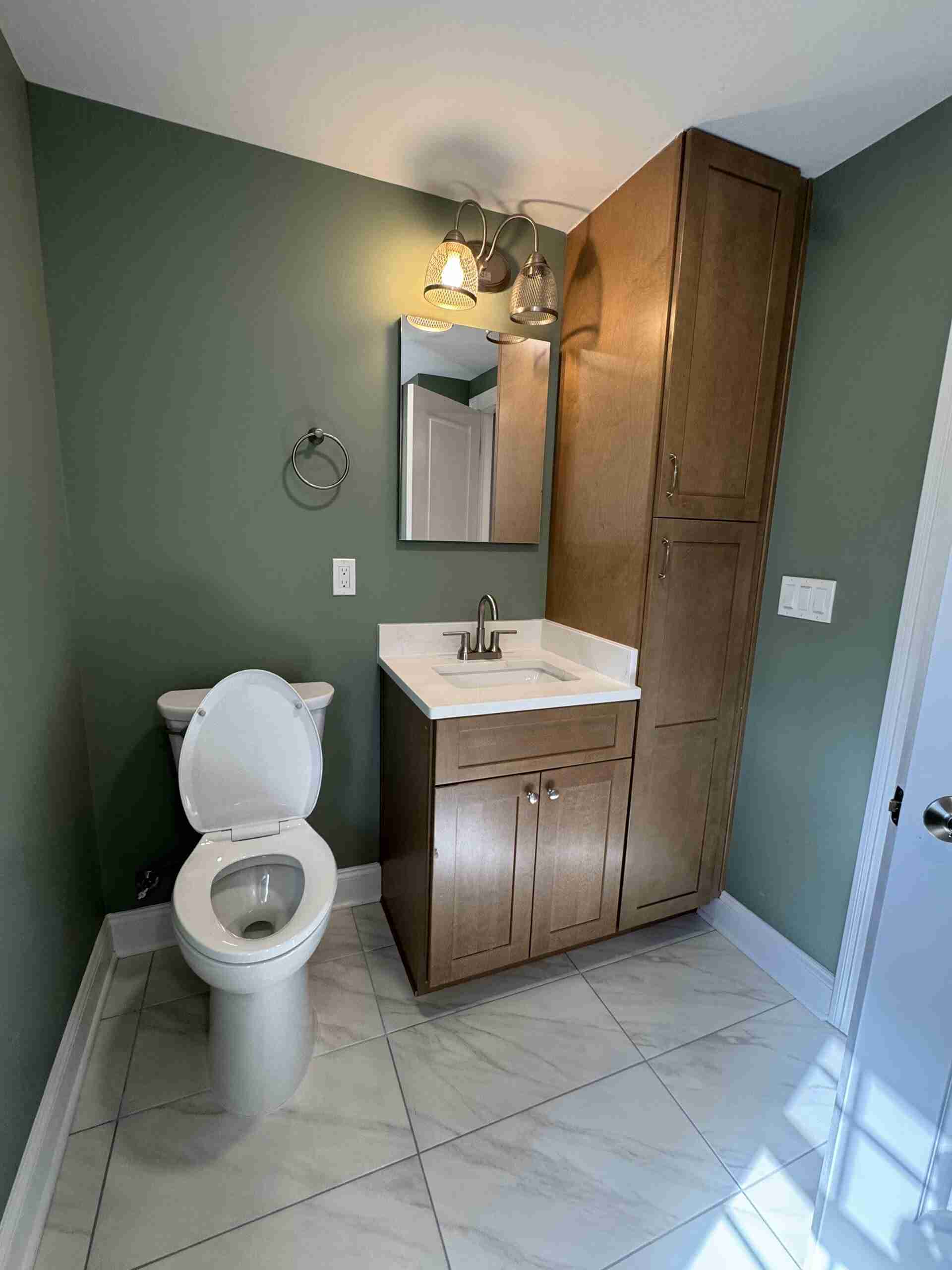 Small guest bathroom renovation featuring green painted wall, wood-cabinets vanity, white tile floor and modern sink.