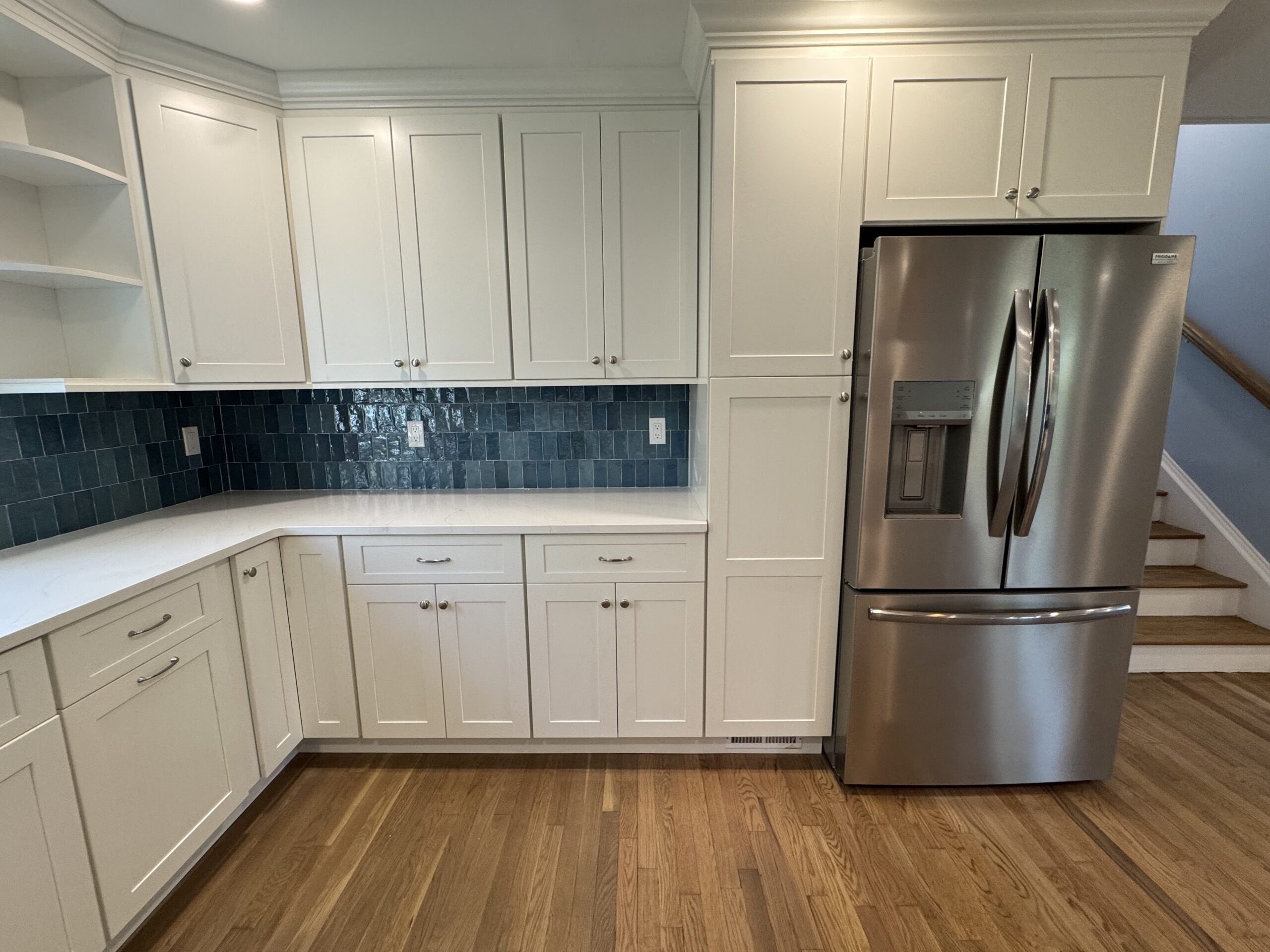 Renovated kitchen featuring white shaker-style cabinetry, white quartz countertops, a navy blue zellige tile backsplash
