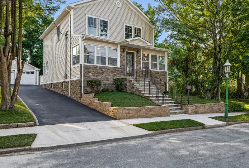 Two-story home with stone accents, paved driveway and landscaped front yard