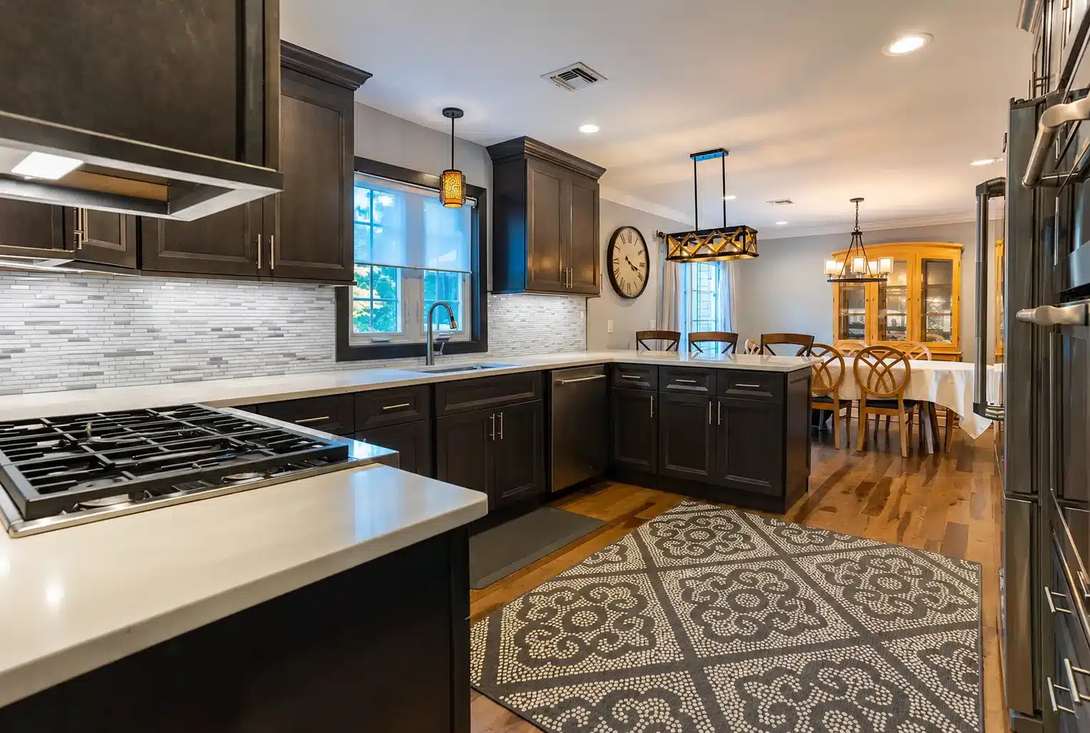 A modern kitchen featuring dark wood cabinets and a spacious central island for cooking and dining.