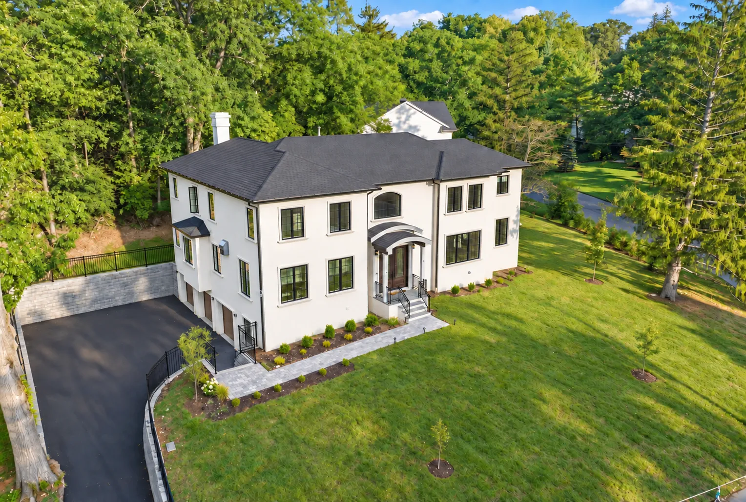 Aerial picture of custom-built home in middle of a lot with large green trees