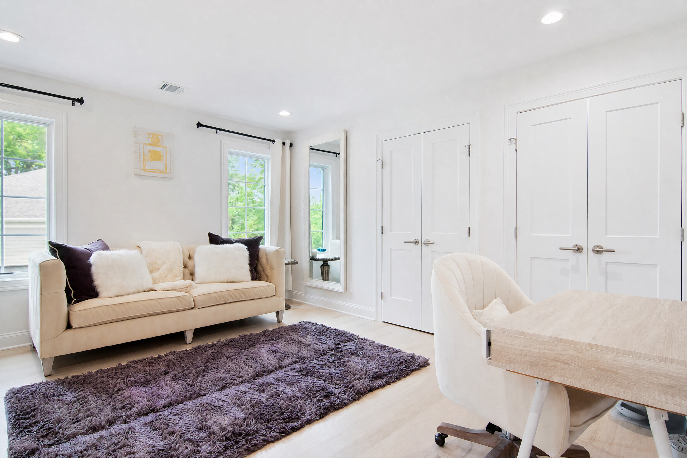 Bonus room in a WA Construct custom home with a tufted sofa, built-in desk area, double closet doors, light hardwood flooring, and white trim.