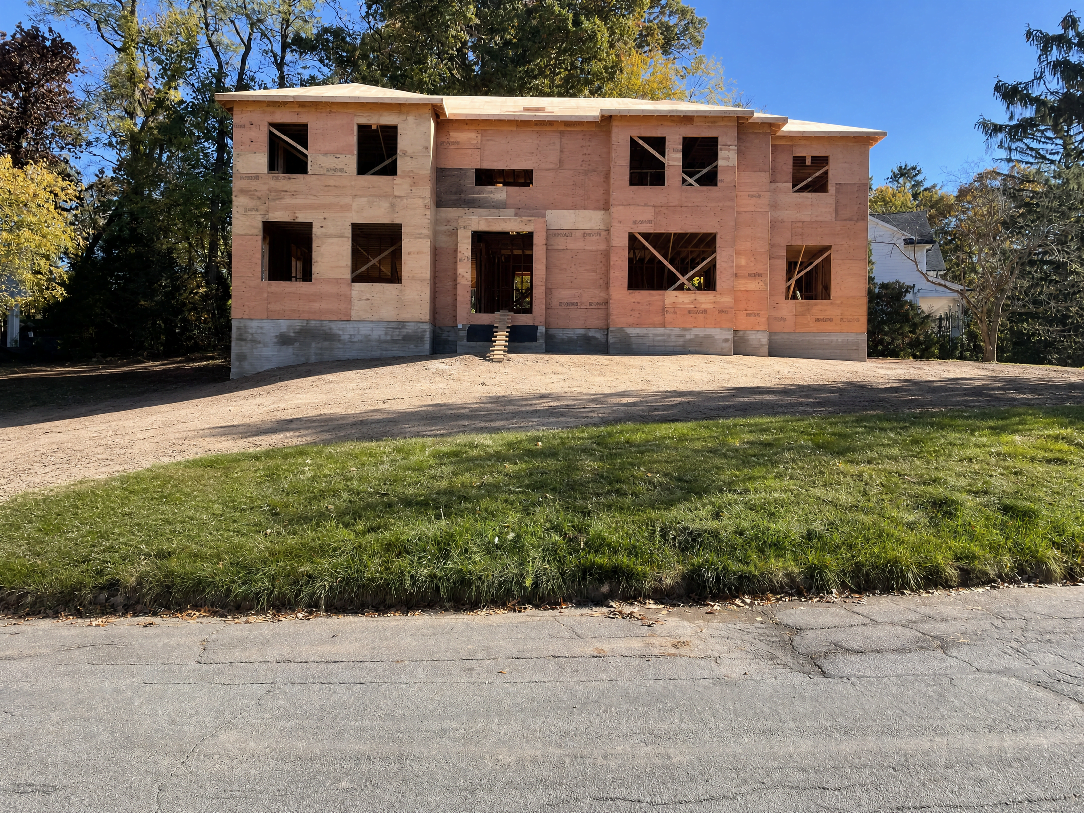 New custom home under construction by WA Construct, showing the front elevation at the framing and sheathing stage with plywood exterior walls, framed window openings, and poured concrete foundation.