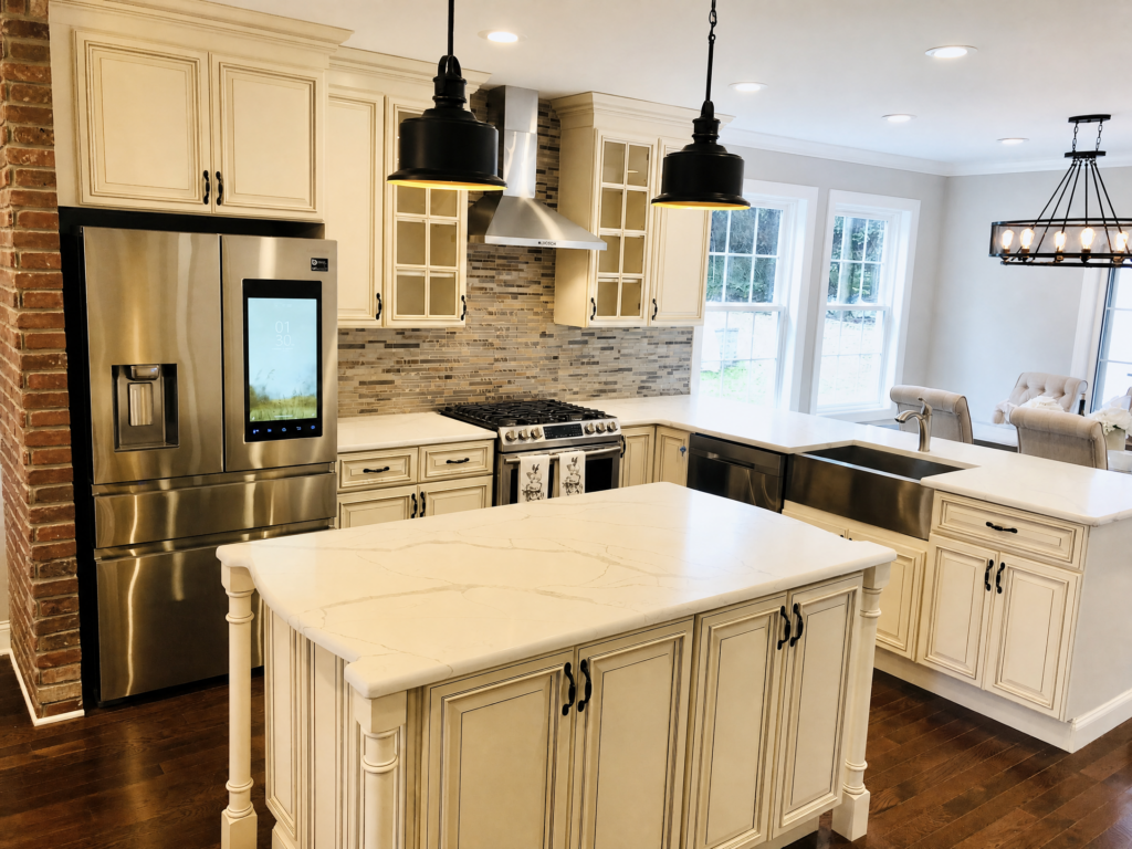 Custom kitchen by WA Construct with cream glazed cabinetry, a quartz-topped center island, stainless steel appliances, farmhouse sink, mosaic tile backsplash, and exposed brick accent wall.