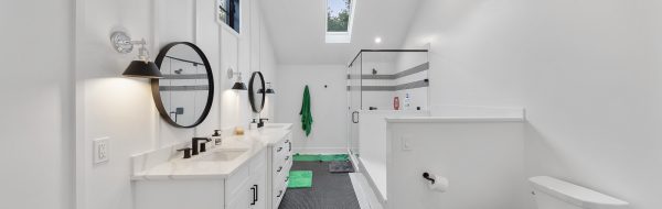 Cream-colored bathroom with evergreen rugs on dual sinks