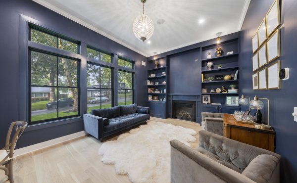 Blue-grey walls, a plush white throw over wood floors, and a golden chandelier in a living room